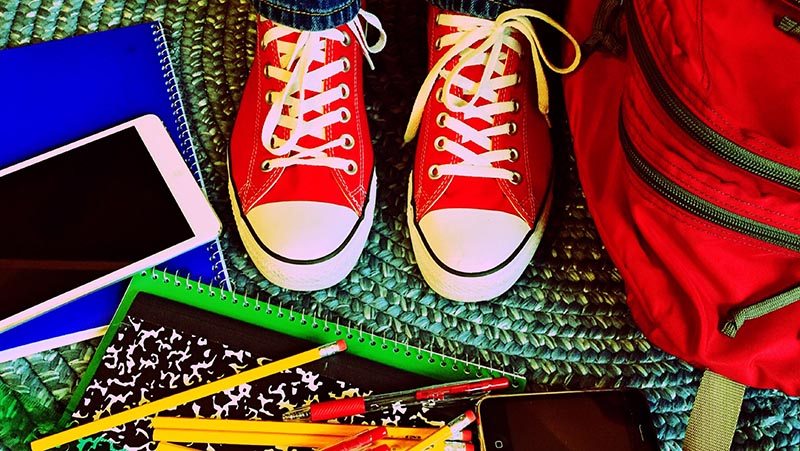 School supplies and red converse on an area rug.
