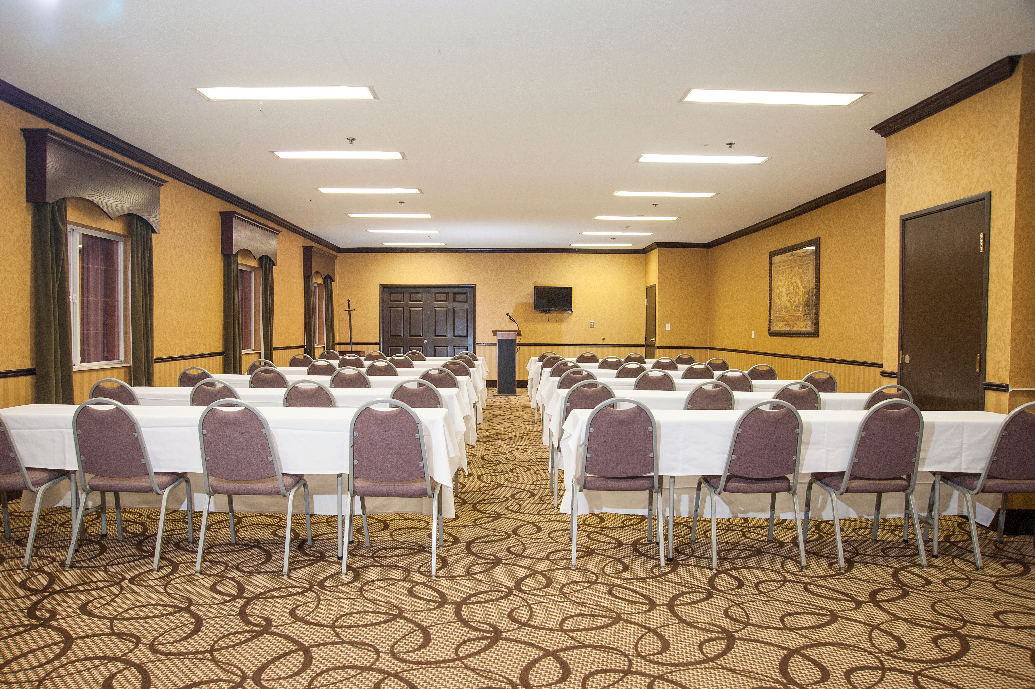 A large meeting room with tables, chairs, and a podium
