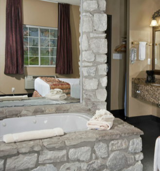 A room with a jetted tub surrounded by beautiful stone work.