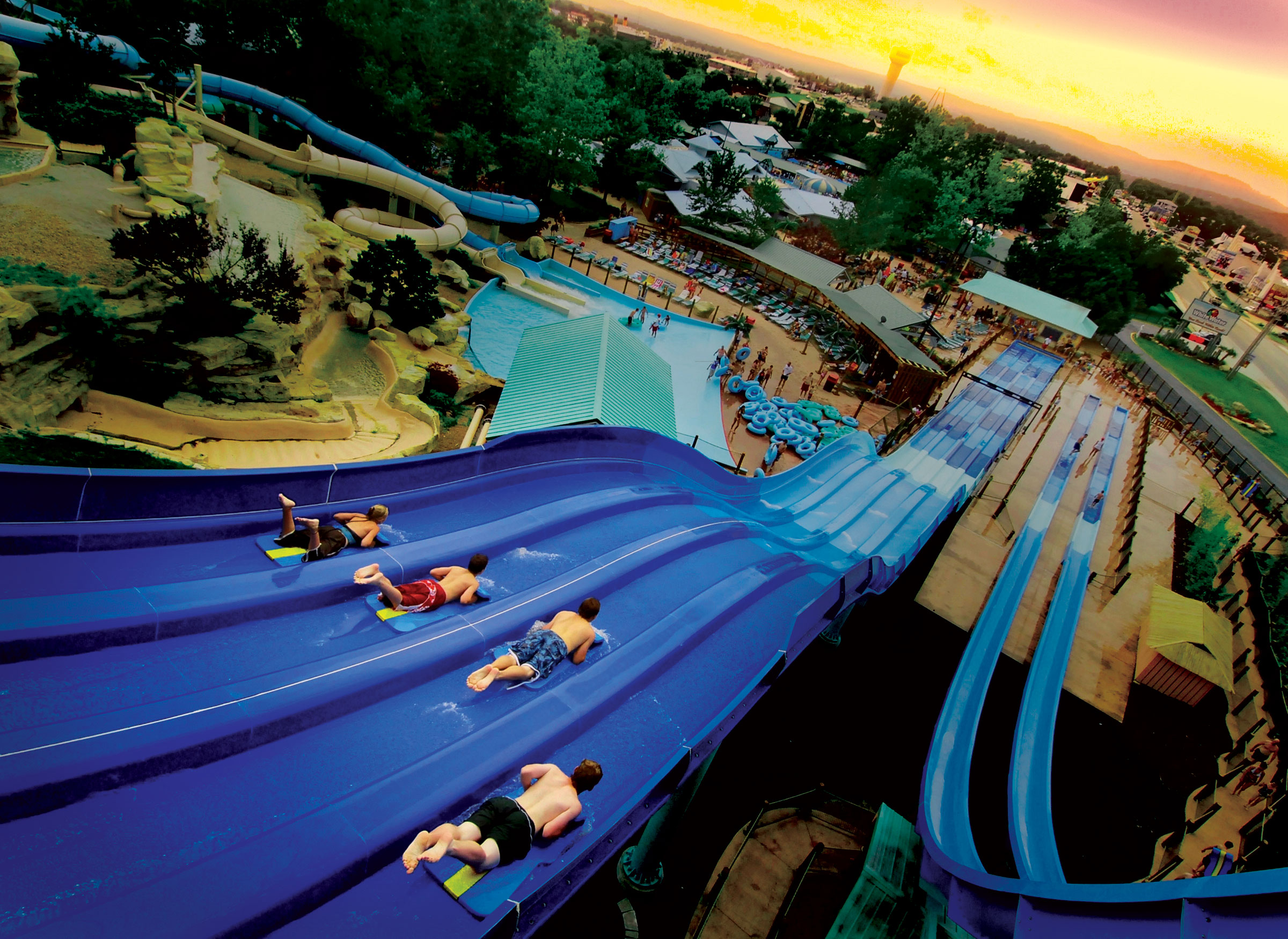 An aerial view of a water park with a large blue water slide and people sliding down it.