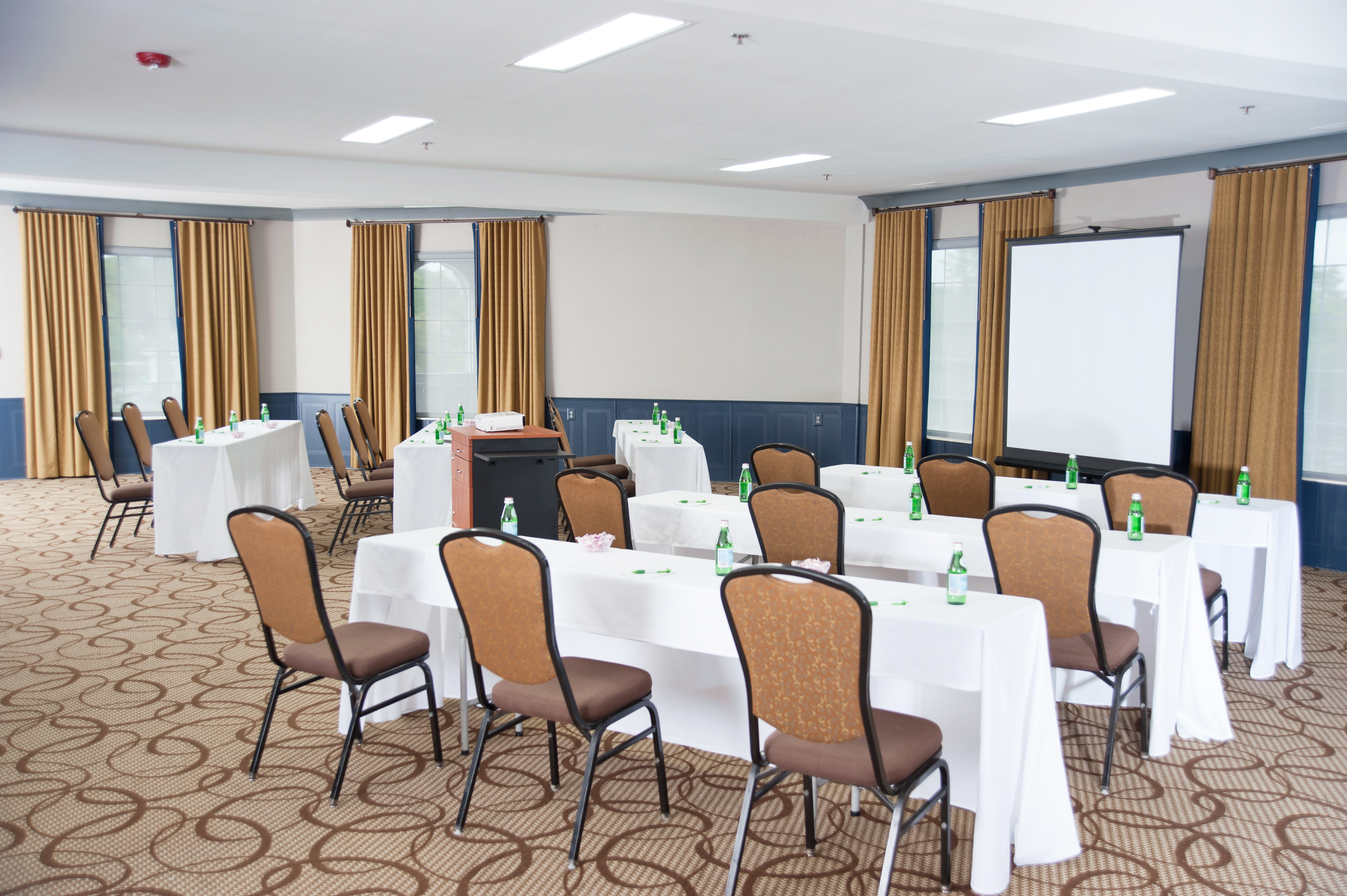 A conference room with white tables, brown chairs, and a whiteboard