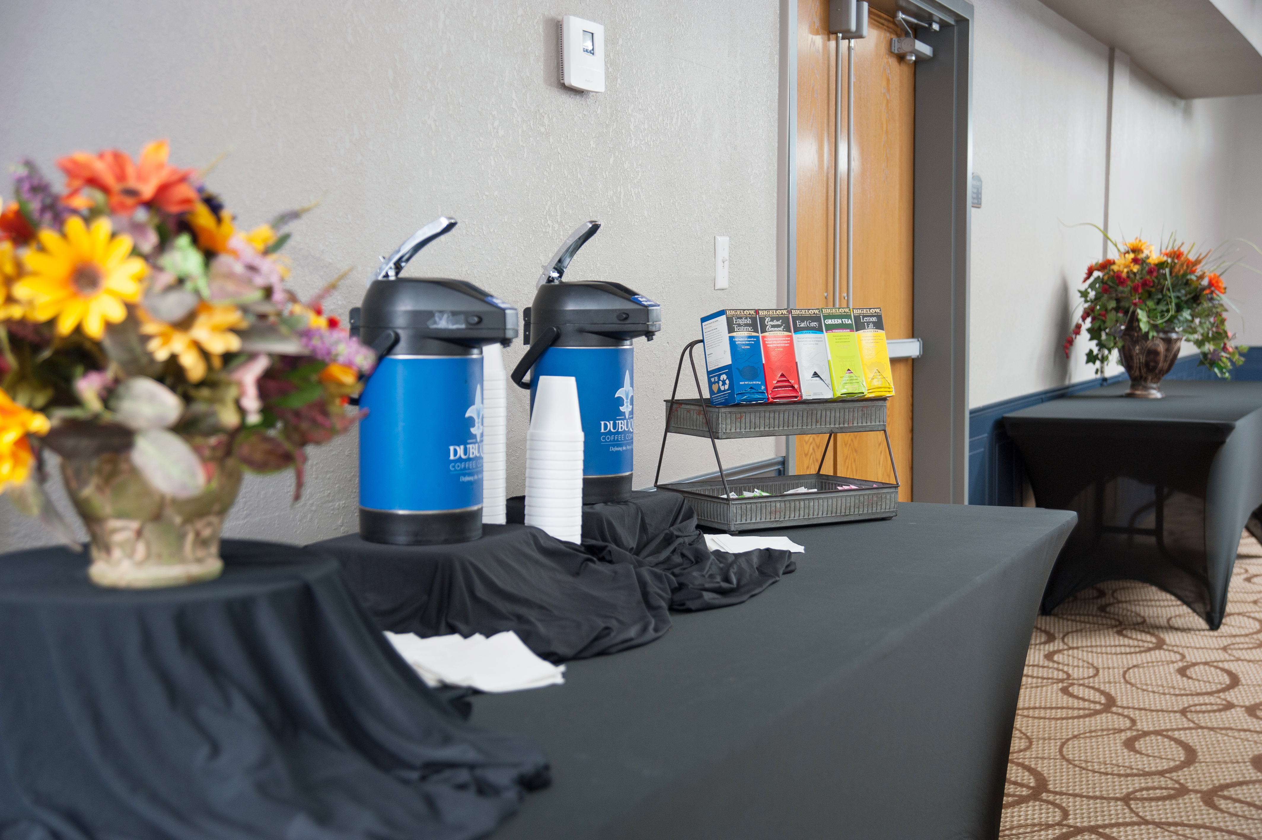 a meeting room setup with coffee urns and flowers
